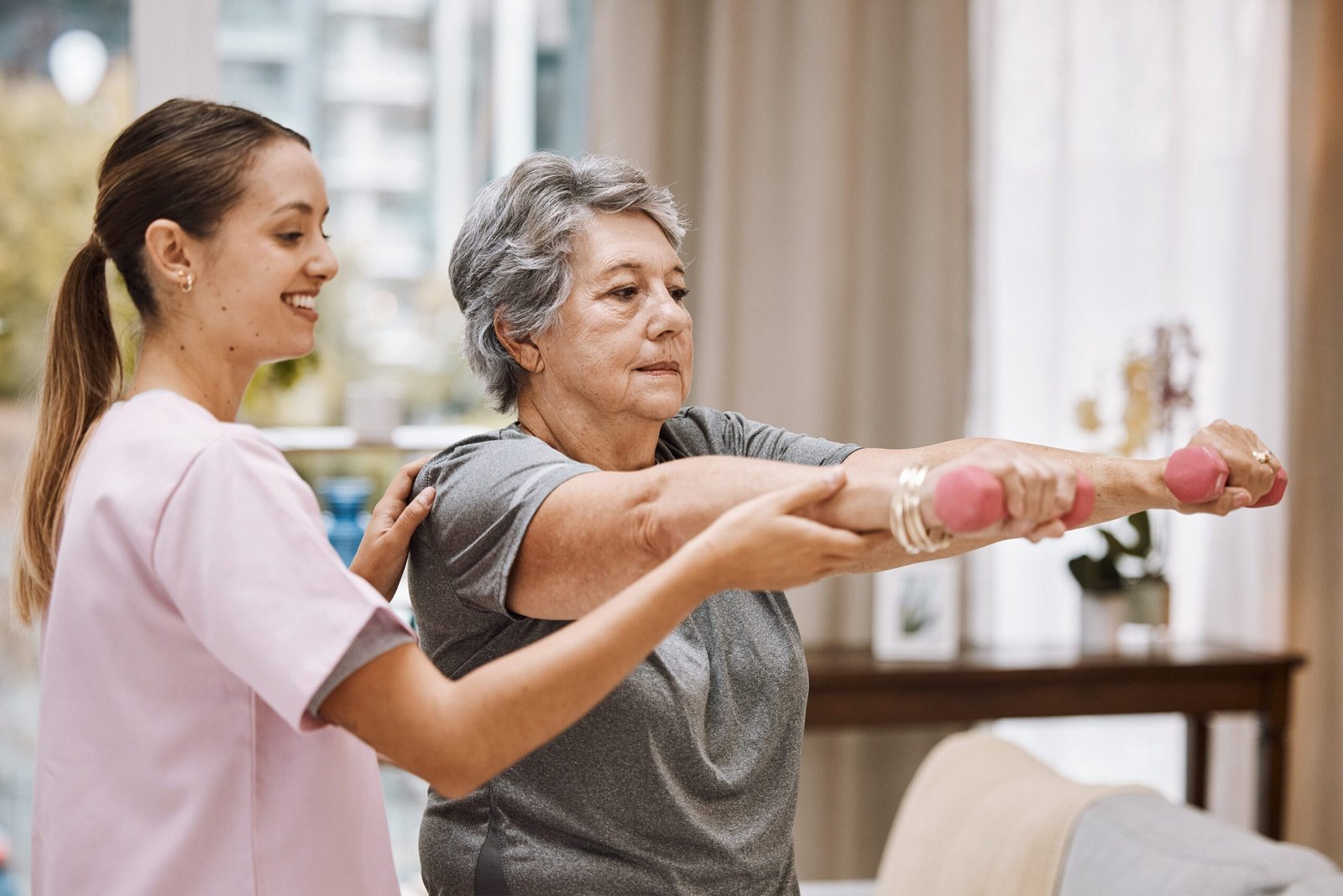 Senior woman doing gentle rehab exercises at home with a trainer