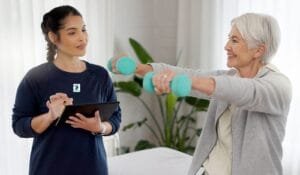 Senior woman lifting dumbbells at home with guidance from a personal trainer in Mississauga