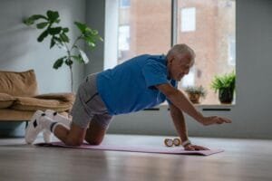 Senior man exercising at home with guidance from an in home personal trainer to improve balance and strength.