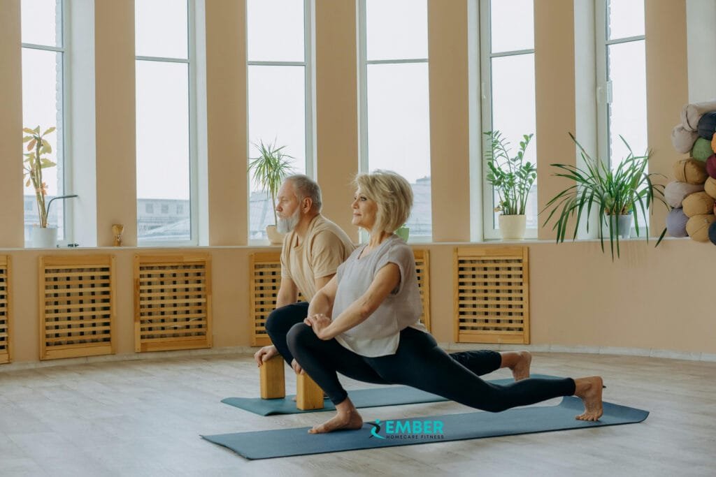Elderly man and woman doing deep lunges with support blocks in a studio