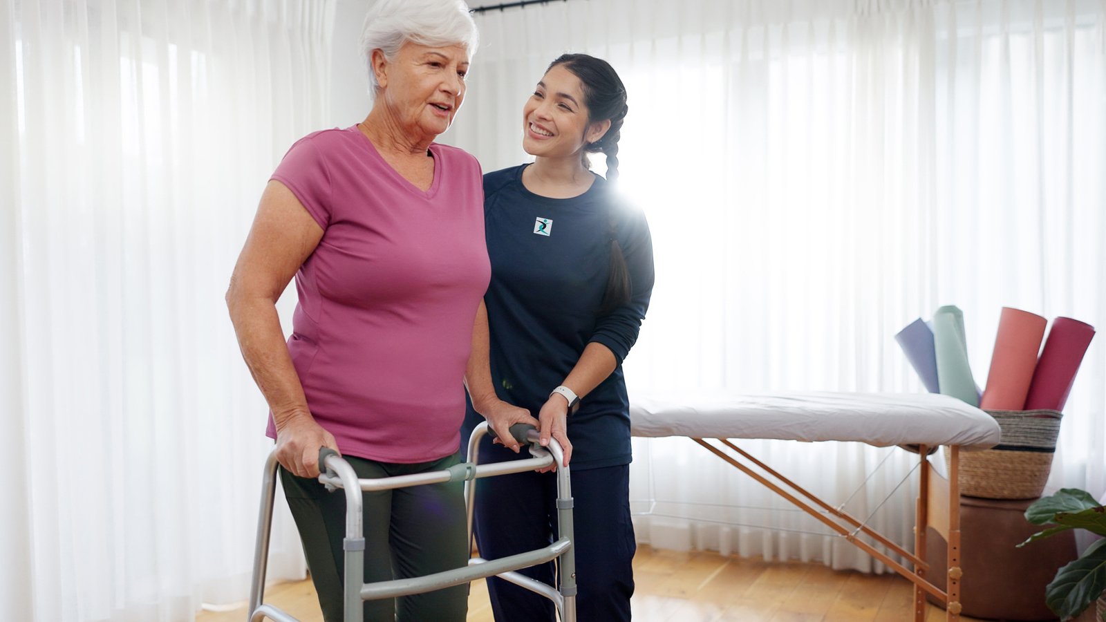Senior woman exercising with resistance bands under the guidance of a personal trainer at home