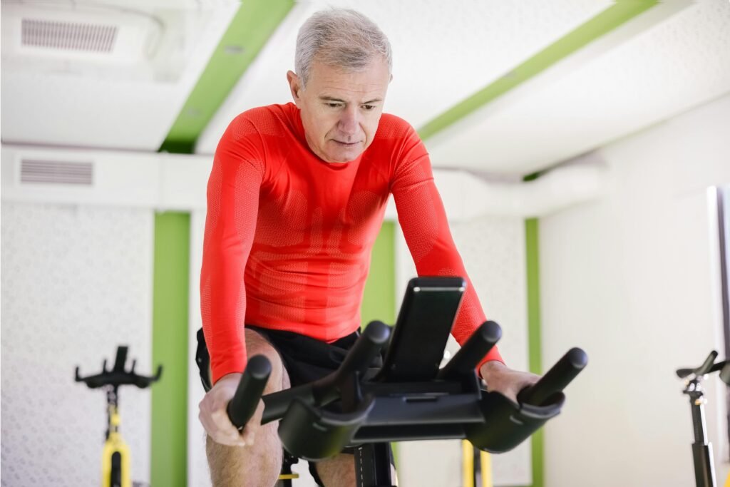 Senior building cardiovascular endurance on a stationary bike, vital for heart health and senior fitness in the GTA.